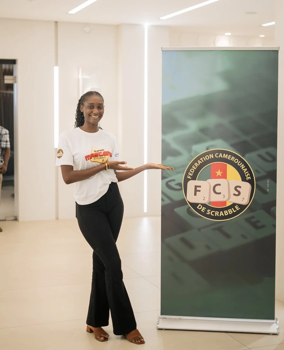 Une hôtesse présente le roll-up de la Fédération Camerounaise de Scrabble