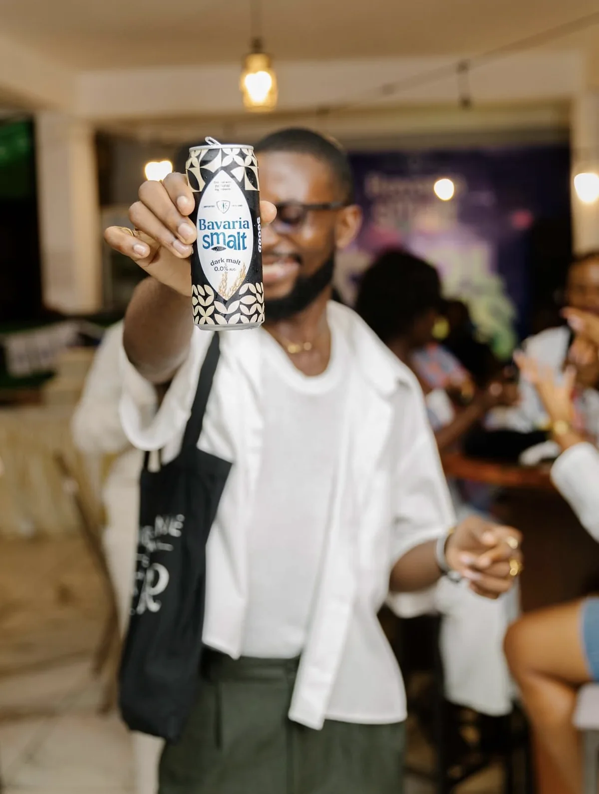 Un invité lève sa canette de Bavaria Smalt pendant la soirée